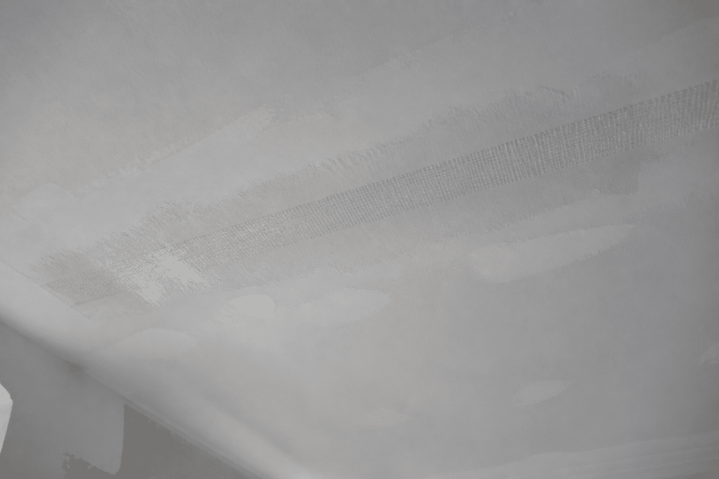 Bande papier mouillée appliquée sur surface de plafond blanc