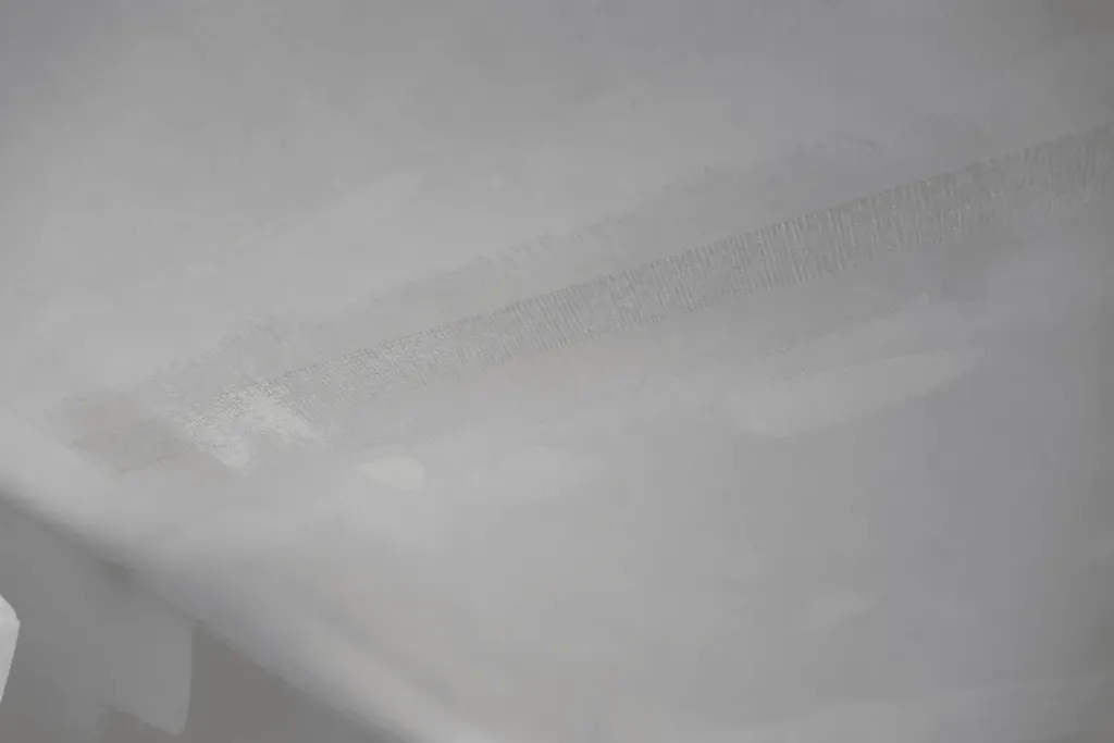 Bande papier mouillée appliquée sur surface de plafond blanc