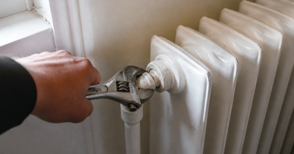 Main tenant une cle ajustable sur robinet radiateur