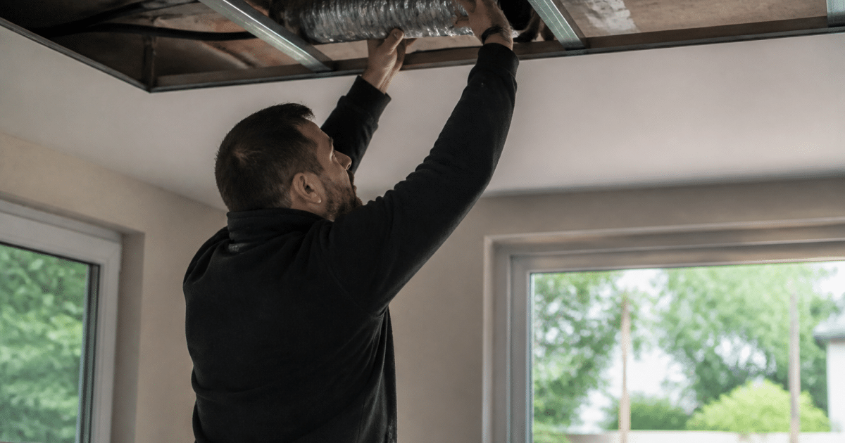 Technicien installant conduit ventilation dans plafond sans demolition