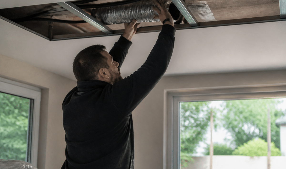Technicien installant conduit ventilation dans plafond sans demolition