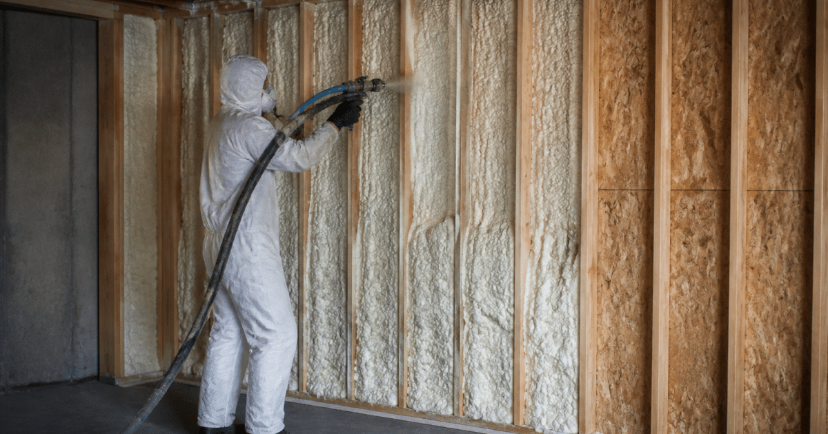 Personne appliquant isolant mousse sur murs garage interieur