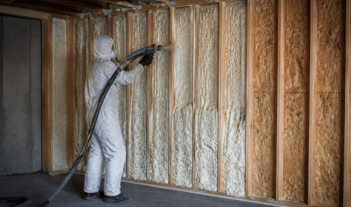 Personne appliquant isolant mousse sur murs garage interieur