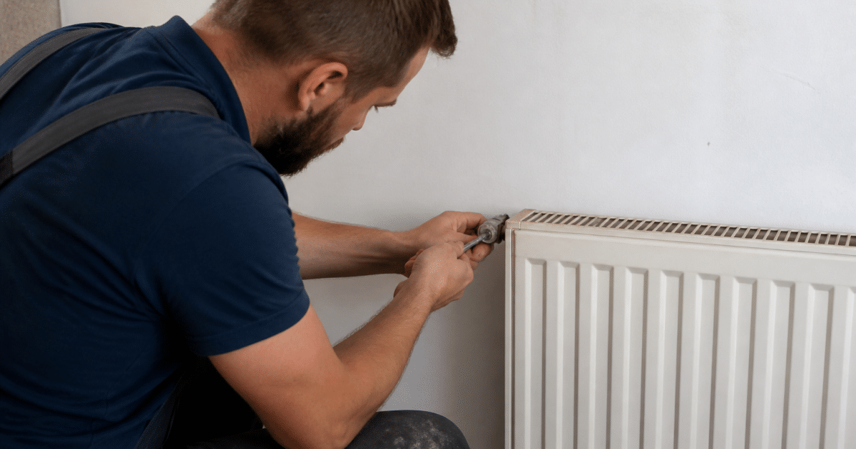 Plombier serrant valve metallique sur radiateur blanc mural