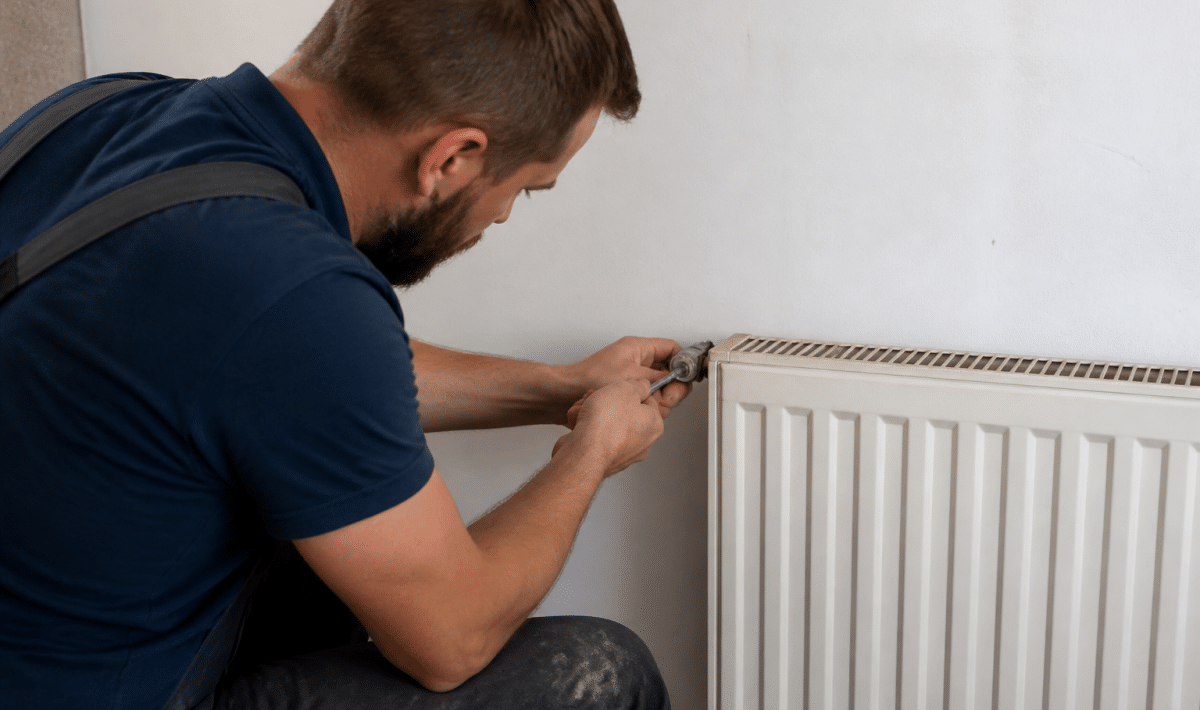 Plombier serrant valve metallique sur radiateur blanc mural