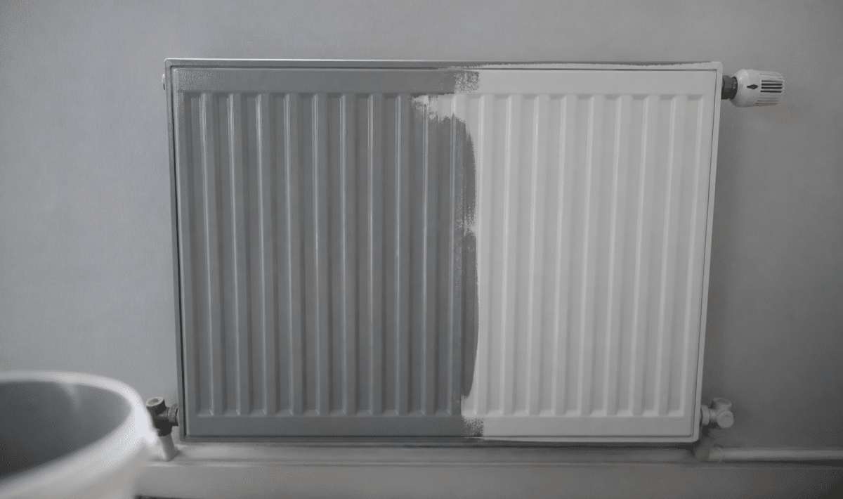 Radiateur blanc mural recouvert partiellement de peinture grise fraiche