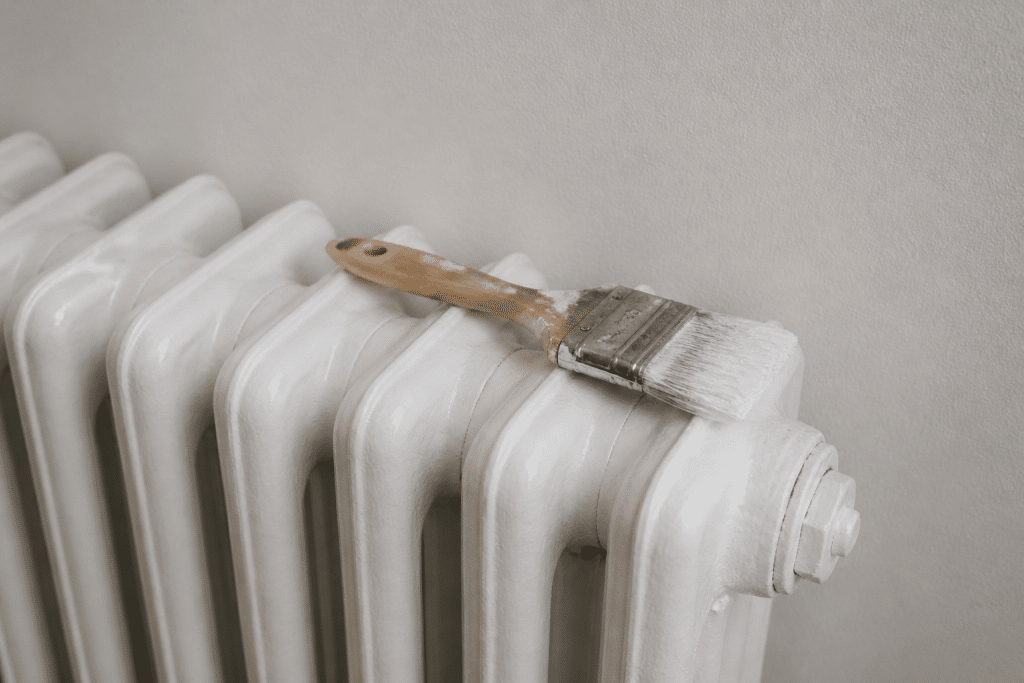Radiateur peint en blanc avec pinceau reposant dessus