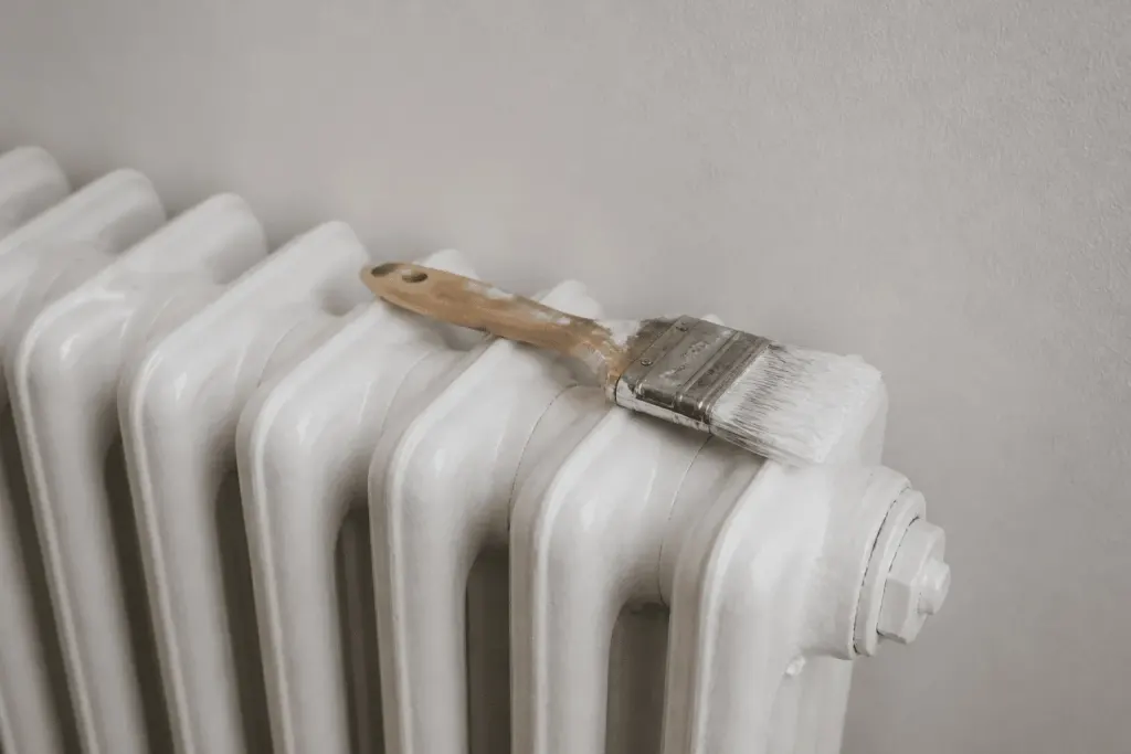 Radiateur peint en blanc avec pinceau reposant dessus