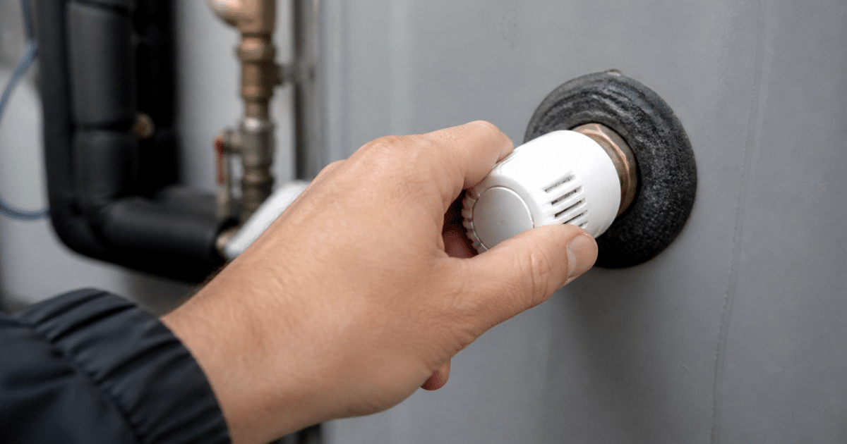 Main serrant le thermostat blanc sur reservoir metallique vertical
