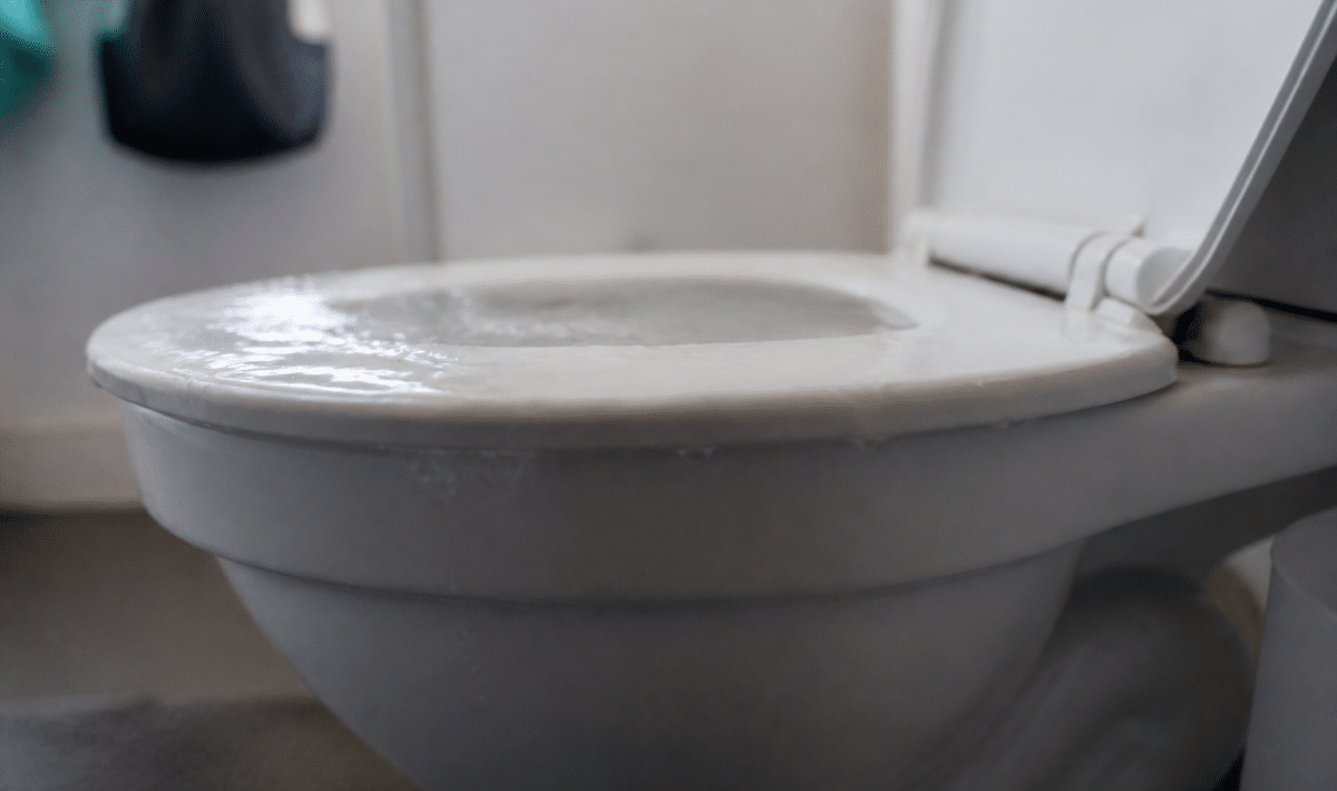 Cuvette toilettes remplie eau débordant au-dessus du rebord blanc