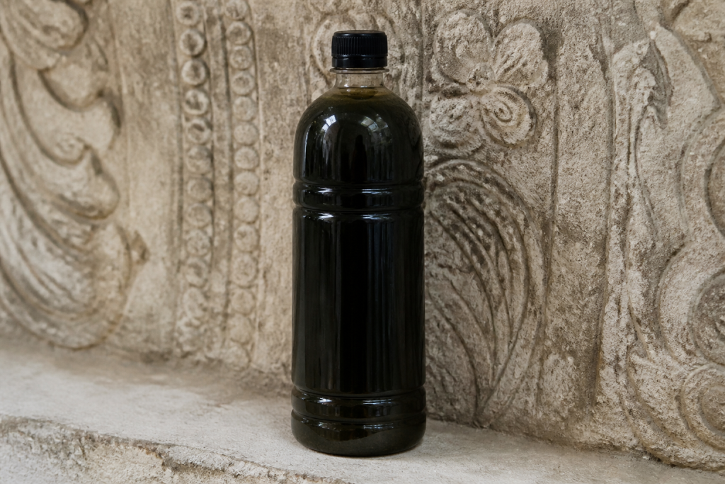 Flacon savon noir devant surface relief texturee