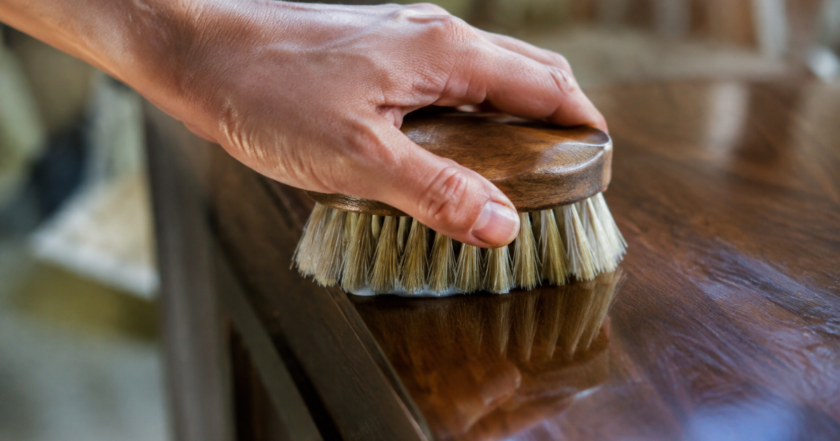 Main avec brosse frottant bois sombre brillant